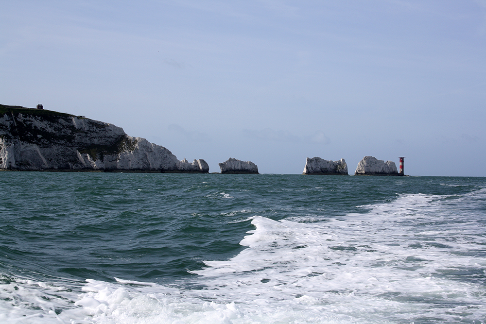 A photograph taken in 2011 from a boat looking south west towards the Needles, Isle of Wight. The chalk stacks of the Needles are shown along with the lighthouse which sits beside the outermost stack.